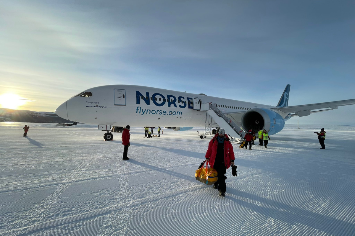 a plane with people standing in the snow