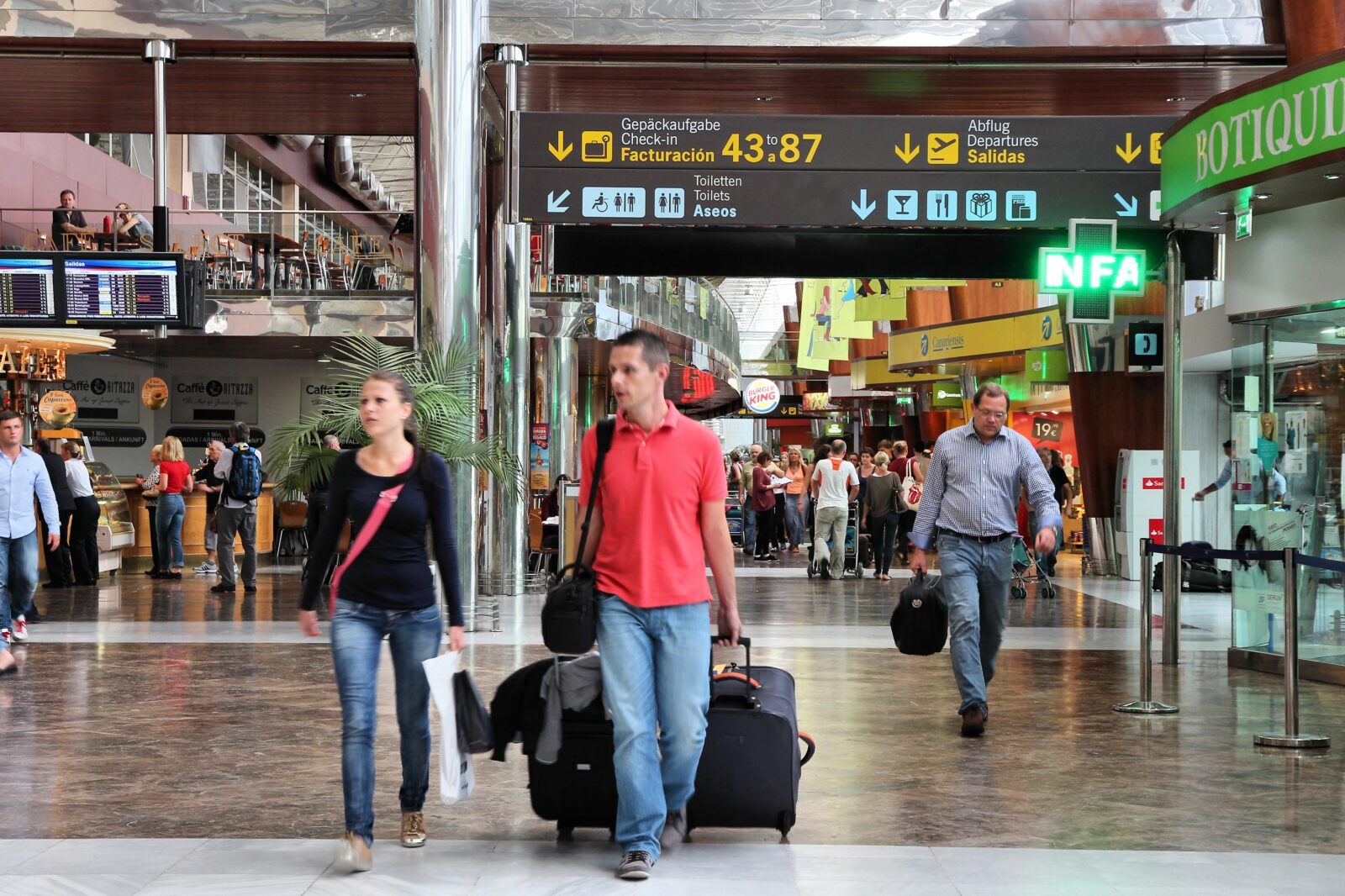 a group of people walking with luggage in a terminal