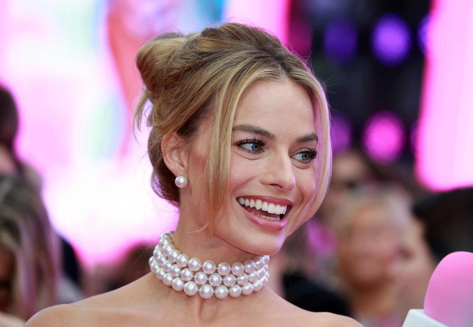 a woman smiling with a pearl necklace
