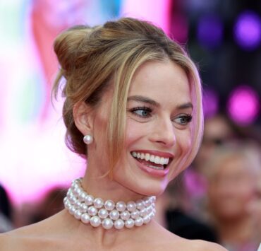 a woman smiling with a pearl necklace