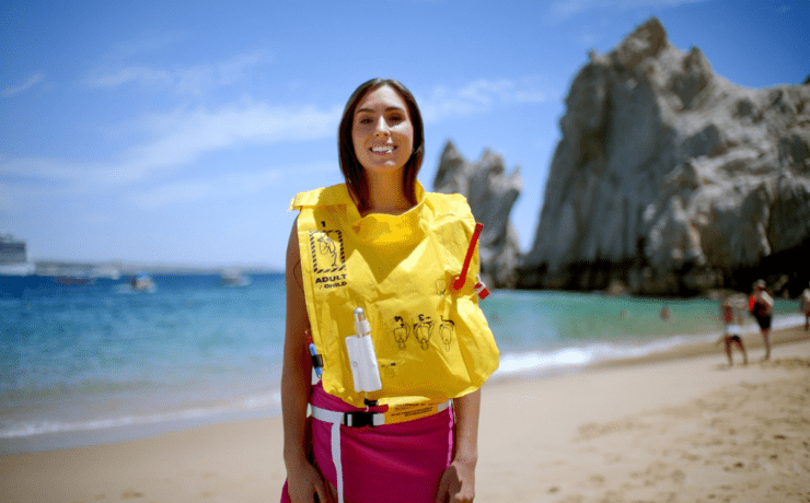 a woman wearing a life jacket on a beach