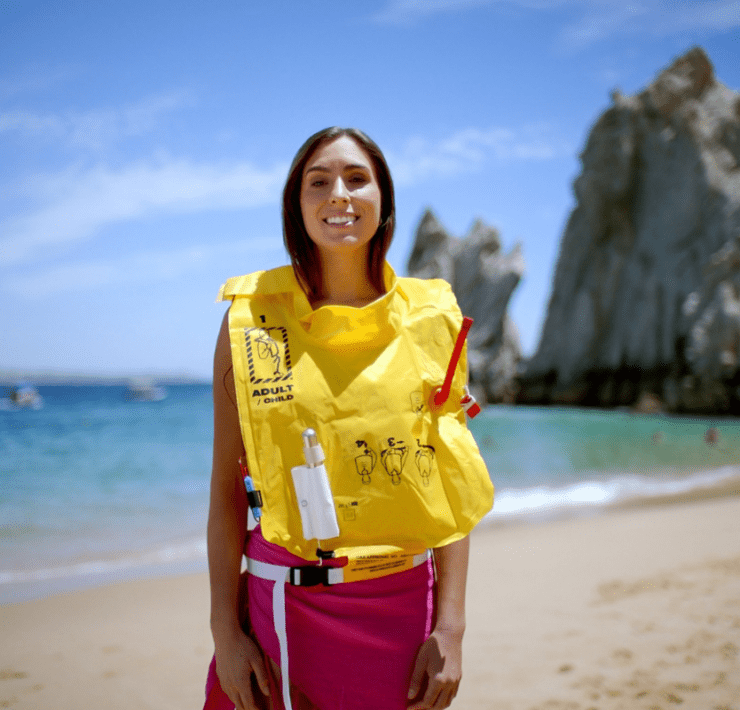 a woman wearing a life jacket on a beach