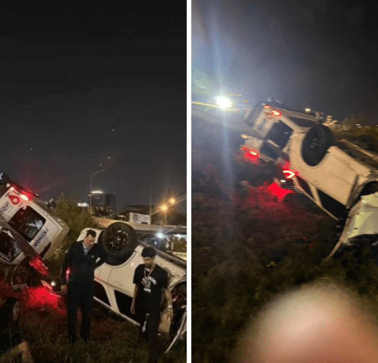 a group of people standing next to a car that crashed into a road