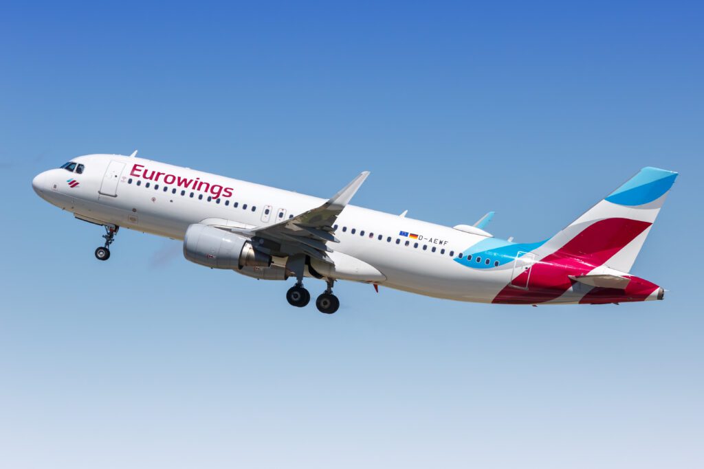 a white airplane with red and blue stripes flying in the sky