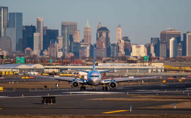 a plane on a runway with a city in the background