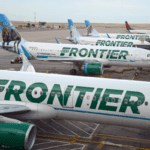 a group of Frontier Airlines airplanes parked on a runway
