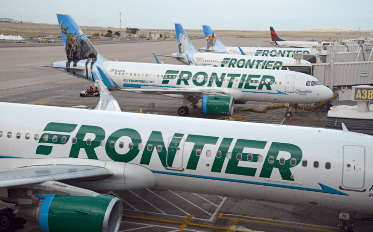 a group of Frontier Airlines airplanes parked on a runway