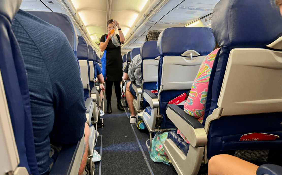 A Southwest Airlines flight attendant stands in the aisle of an airplane while performing the safety demonstration