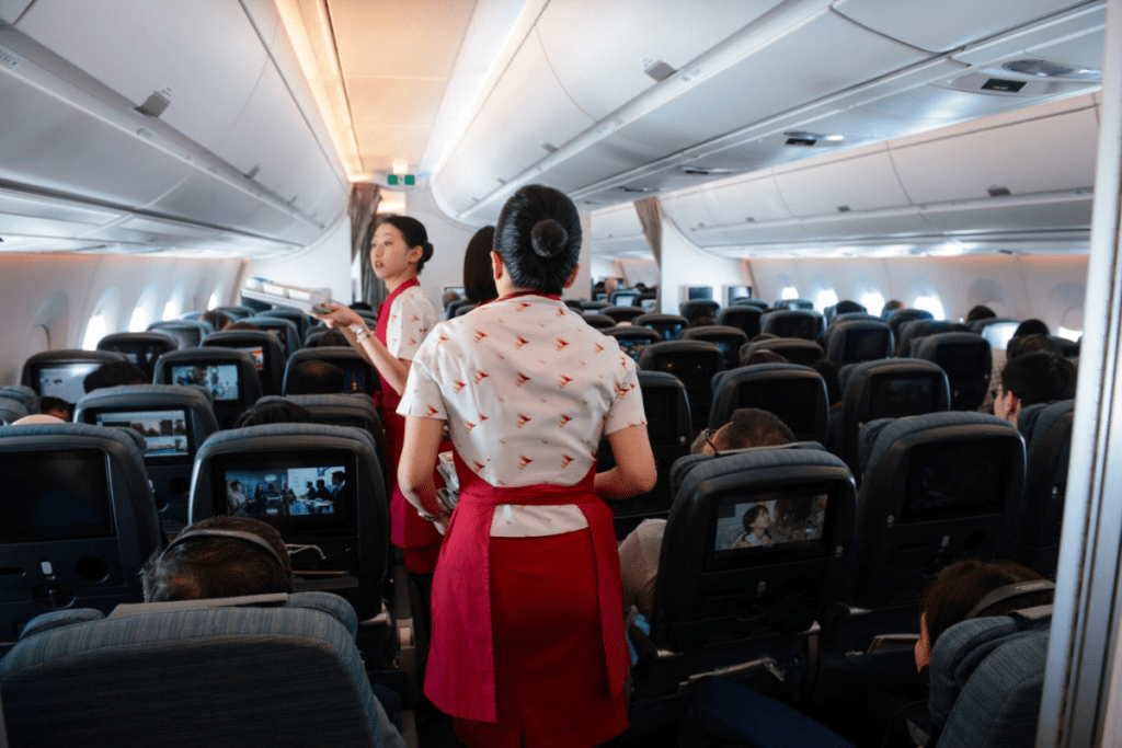 Cathay Pacific flight attendants serving passengers onboard an airplane.