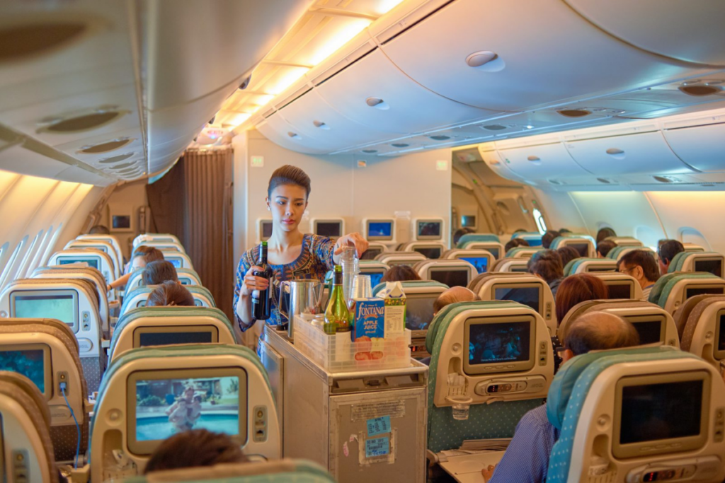 A Singapore Airlines flight attendants serving drinks from a beverage cart