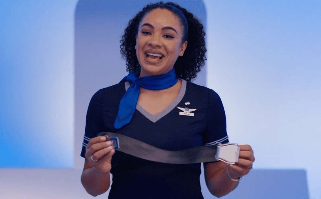 A United Airlines flight attendant holding up a seat belt