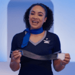 A United Airlines flight attendant holding up a seat belt
