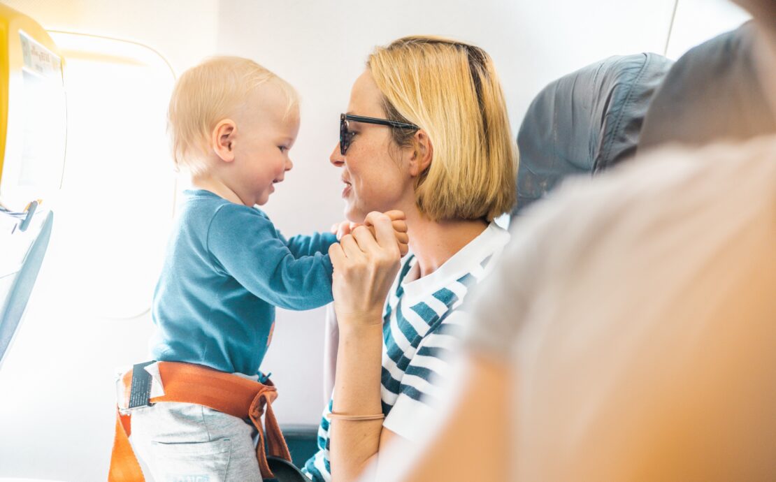 a woman holding a baby on an airplane with an extension seatbelt around the infant
