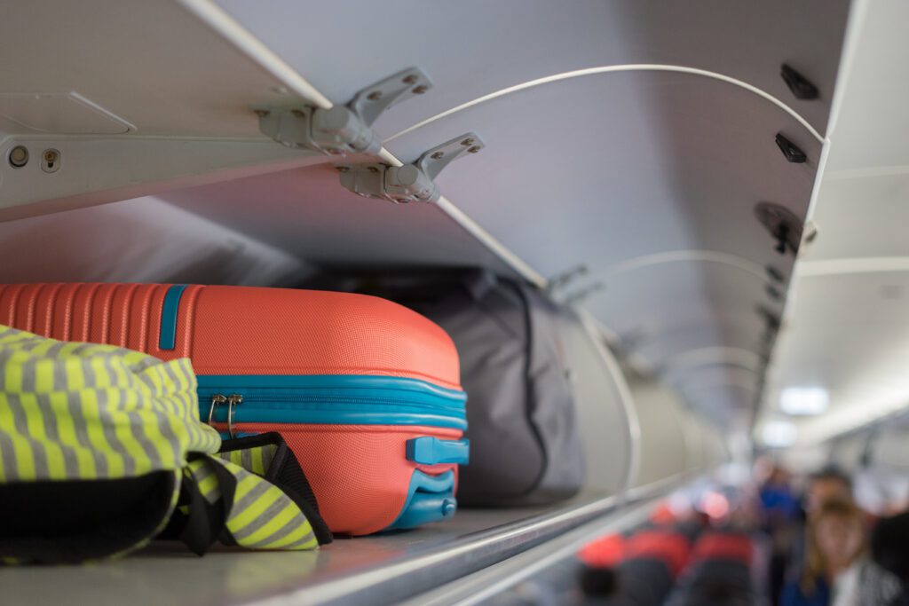 hand luggage in an overhead bin in the passenger cabin of an airplane