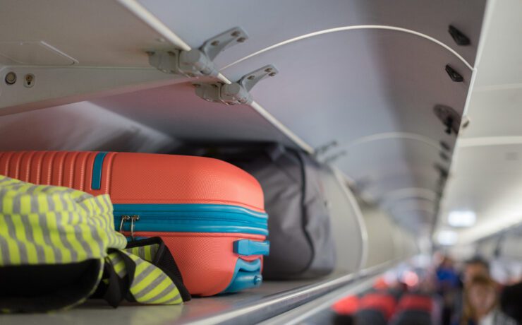 hand luggage in an overhead bin in the passenger cabin of an airplane