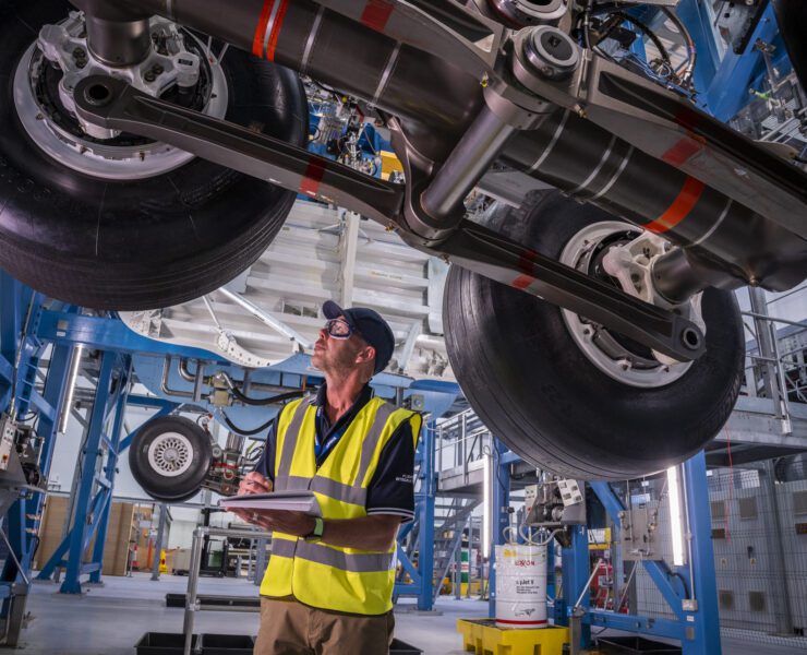 a man in a safety vest and hat standing under a large machine