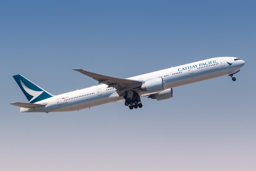 A Cathay Pacific Boeing 777 taking off against a blue sky