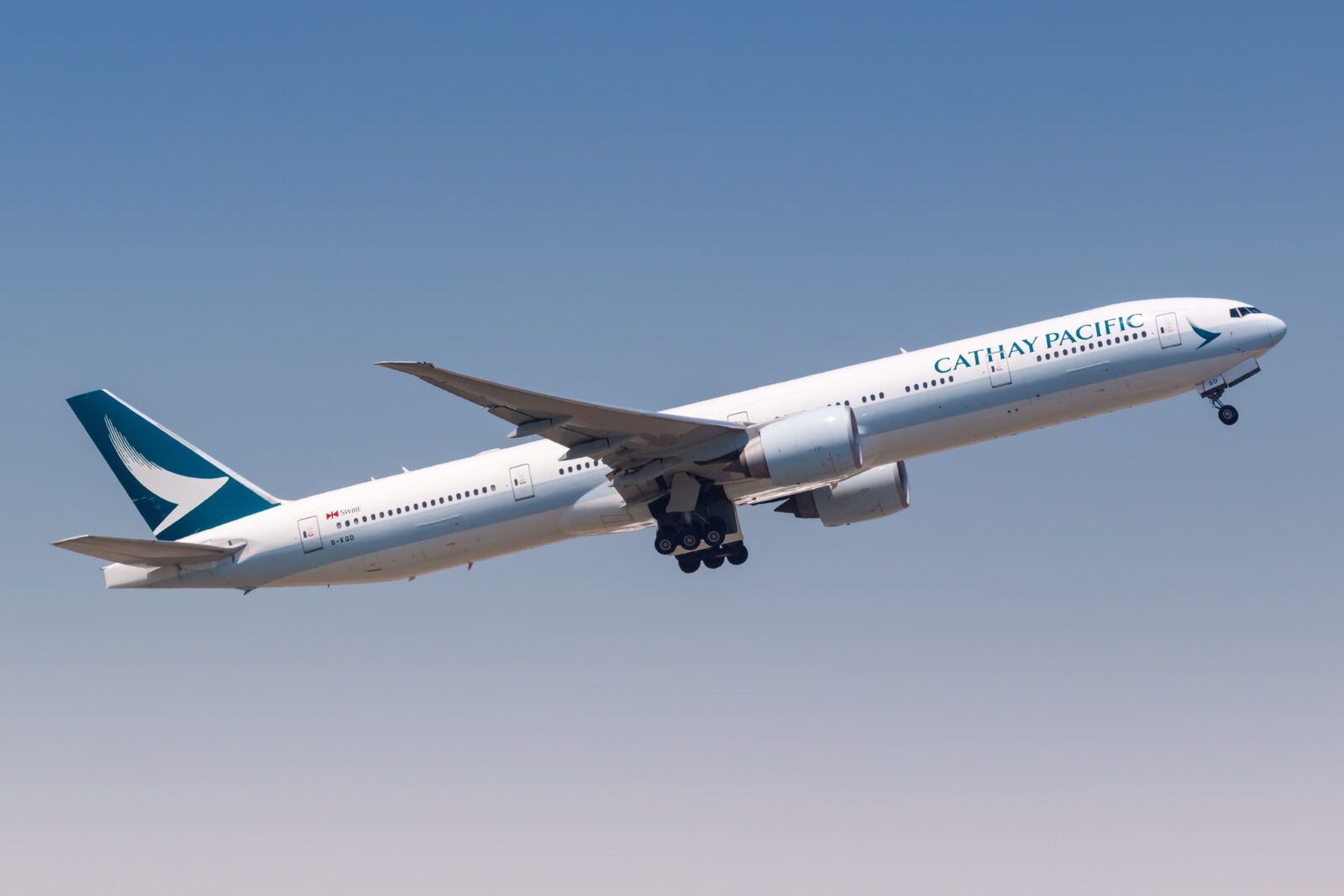 A Cathay Pacific Boeing 777 taking off against a blue sky