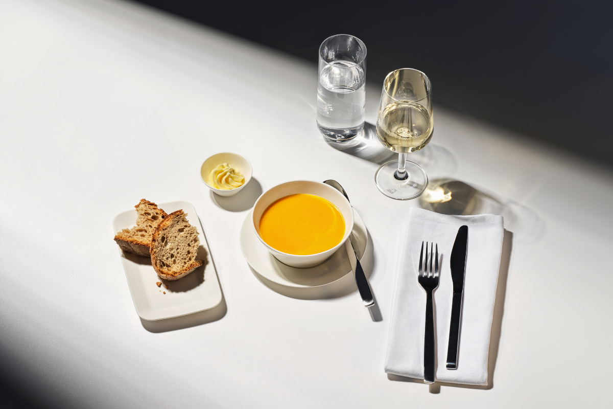 a bowl of soup and bread on a plate with a fork and knife