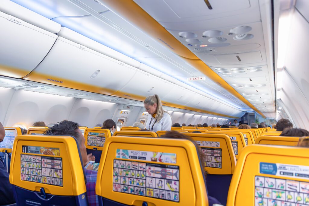 backs of ryanair seats with a flight attendant in the background