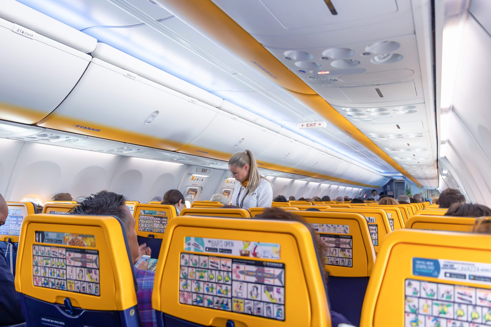 backs of ryanair seats with a flight attendant in the background