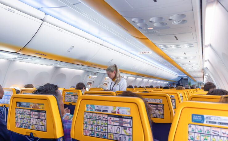 backs of ryanair seats with a flight attendant in the background