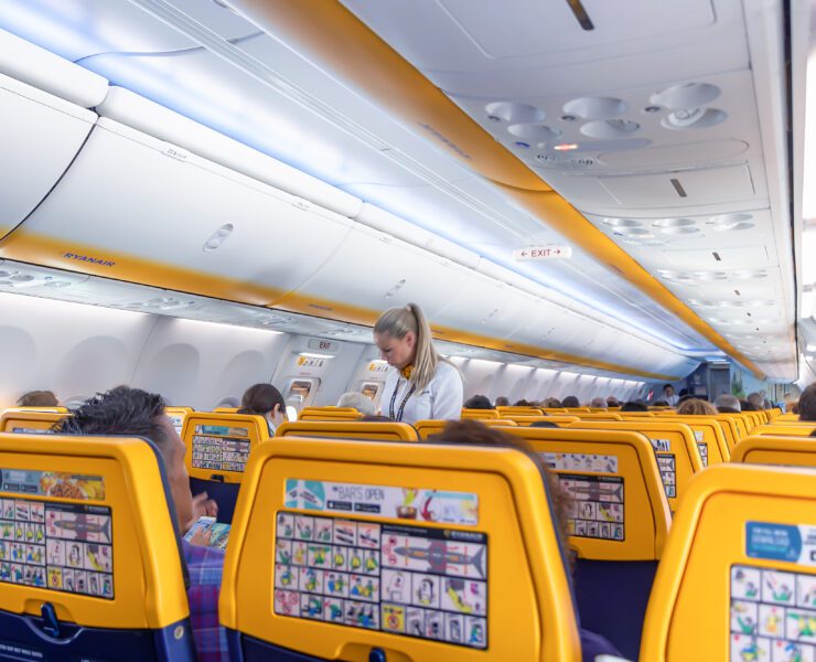 backs of ryanair seats with a flight attendant in the background
