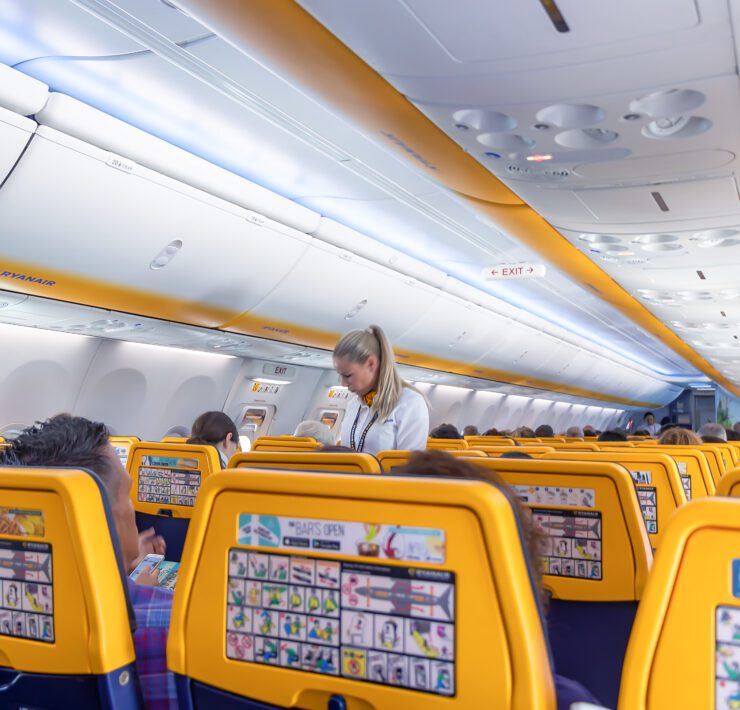 backs of ryanair seats with a flight attendant in the background