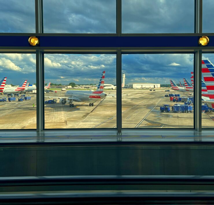 a group of american airlines planes on the tarmac at Charlotte Airport, as seen through a window in the terminal
