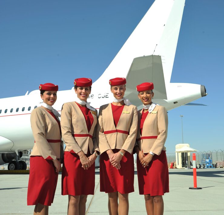 a group of women in red and tan uniforms standing in front of a plane