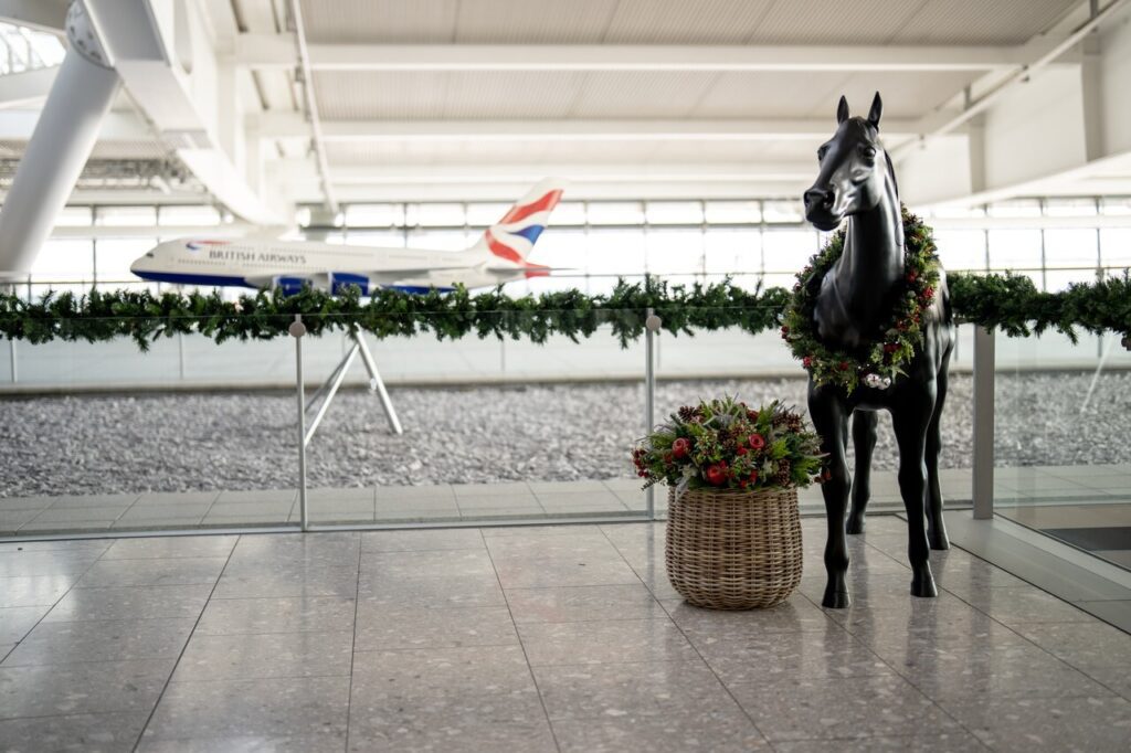 a statue of a horse with a wreath and a basket of flowers in front of a plane