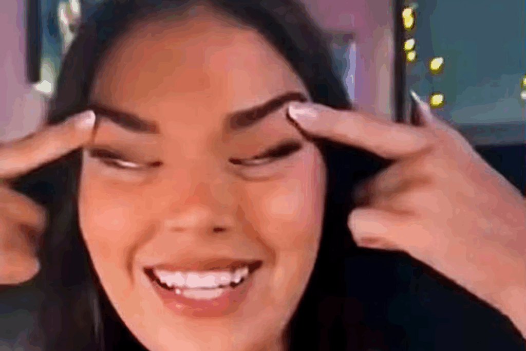 a woman smiling with her fingers on her eyebrow