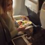 a woman sitting in an airplane eating food