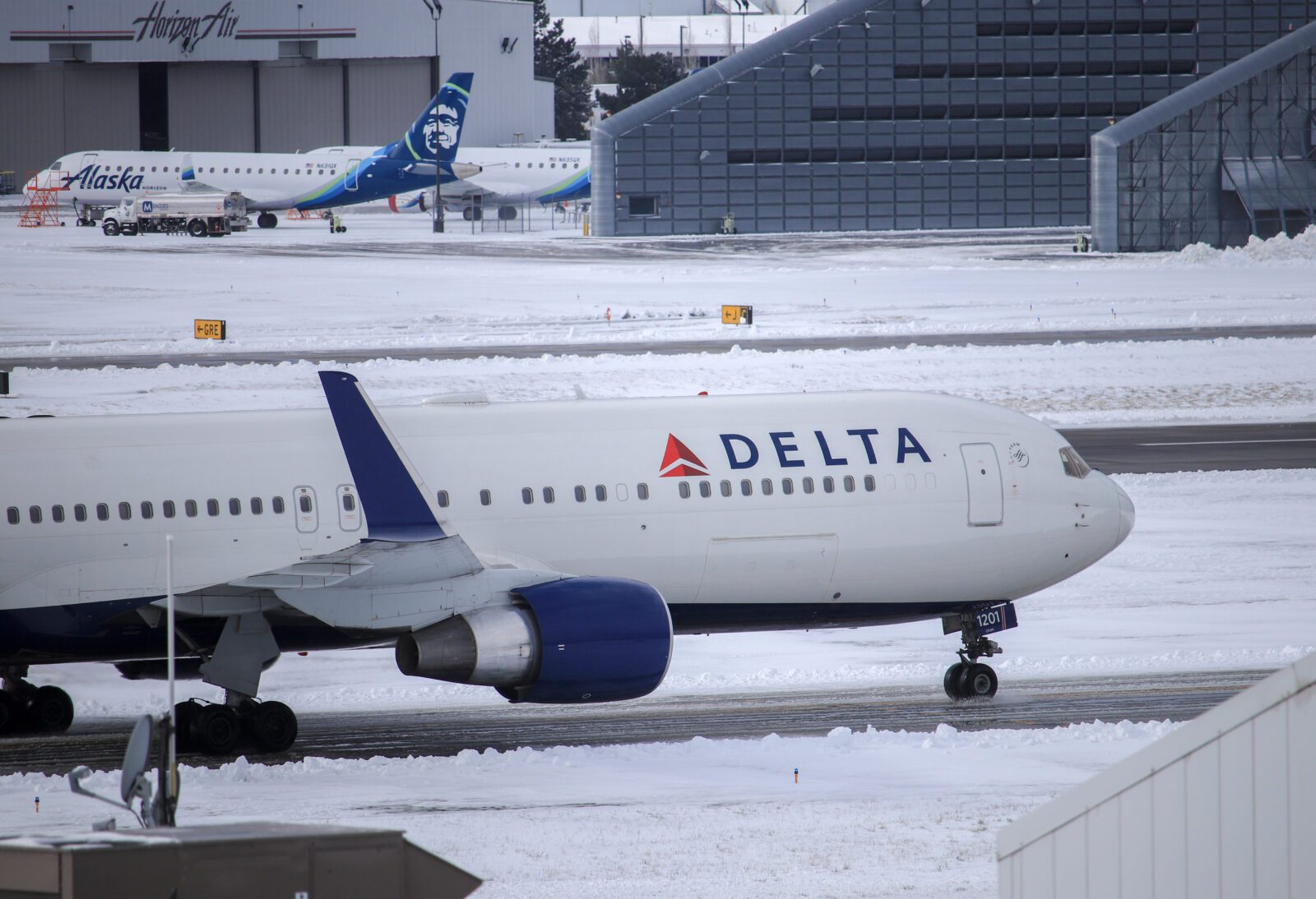 a delta air lines plane in snowy conditions taxiing on the runway