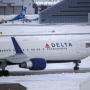 a delta air lines plane in snowy conditions taxiing on the runway