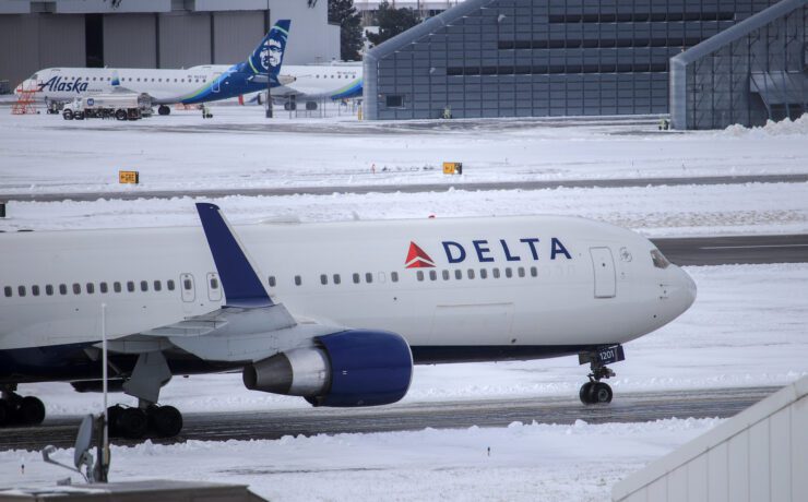 a delta air lines plane in snowy conditions taxiing on the runway