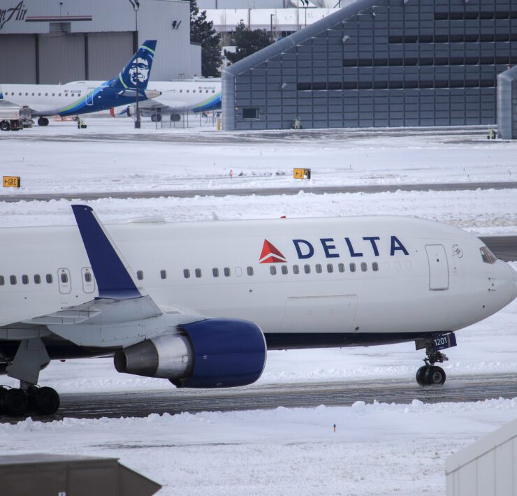 a delta air lines plane in snowy conditions taxiing on the runway