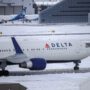 a delta air lines plane in snowy conditions taxiing on the runway
