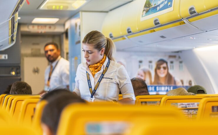 Two Ryanair cabin crew in amongst seats on a plane