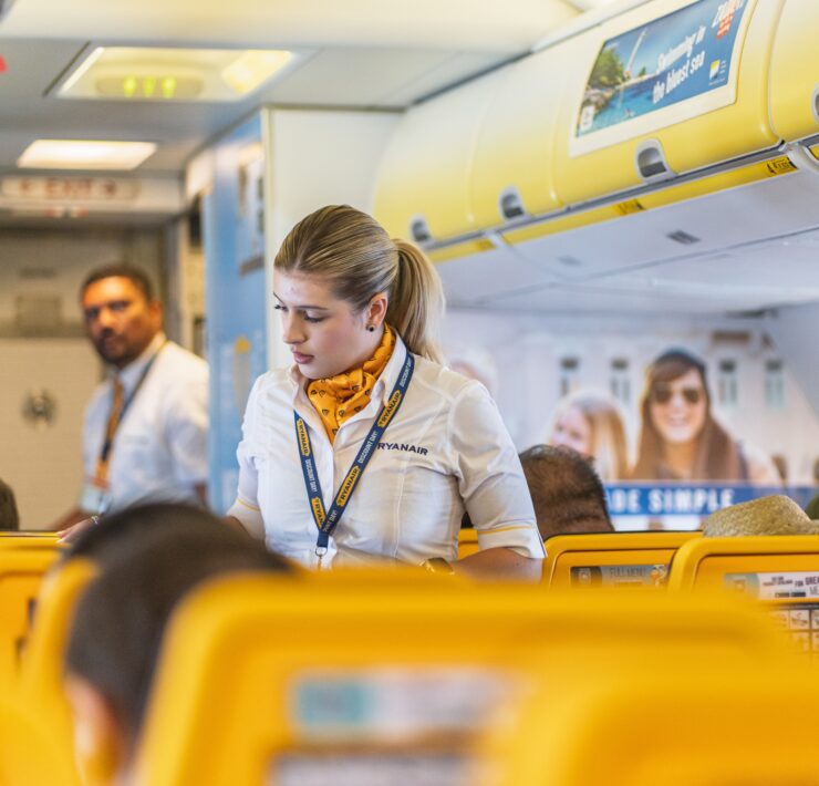 Two Ryanair cabin crew in amongst seats on a plane