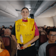 a woman in a yellow life vest standing in a plane