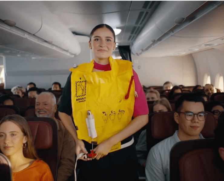 a woman in a yellow life vest standing in a plane