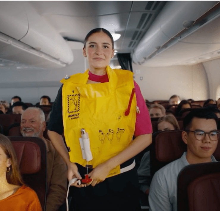 a woman in a yellow life vest standing in a plane