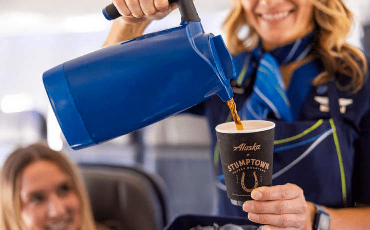 An Alaska Airlines flight attendant poring coffee