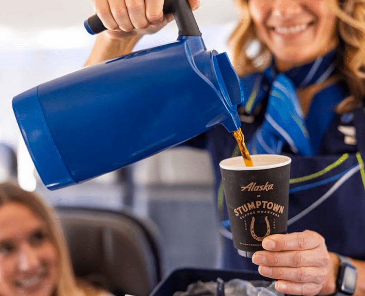 An Alaska Airlines flight attendant poring coffee