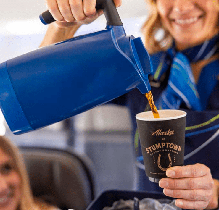 An Alaska Airlines flight attendant poring coffee