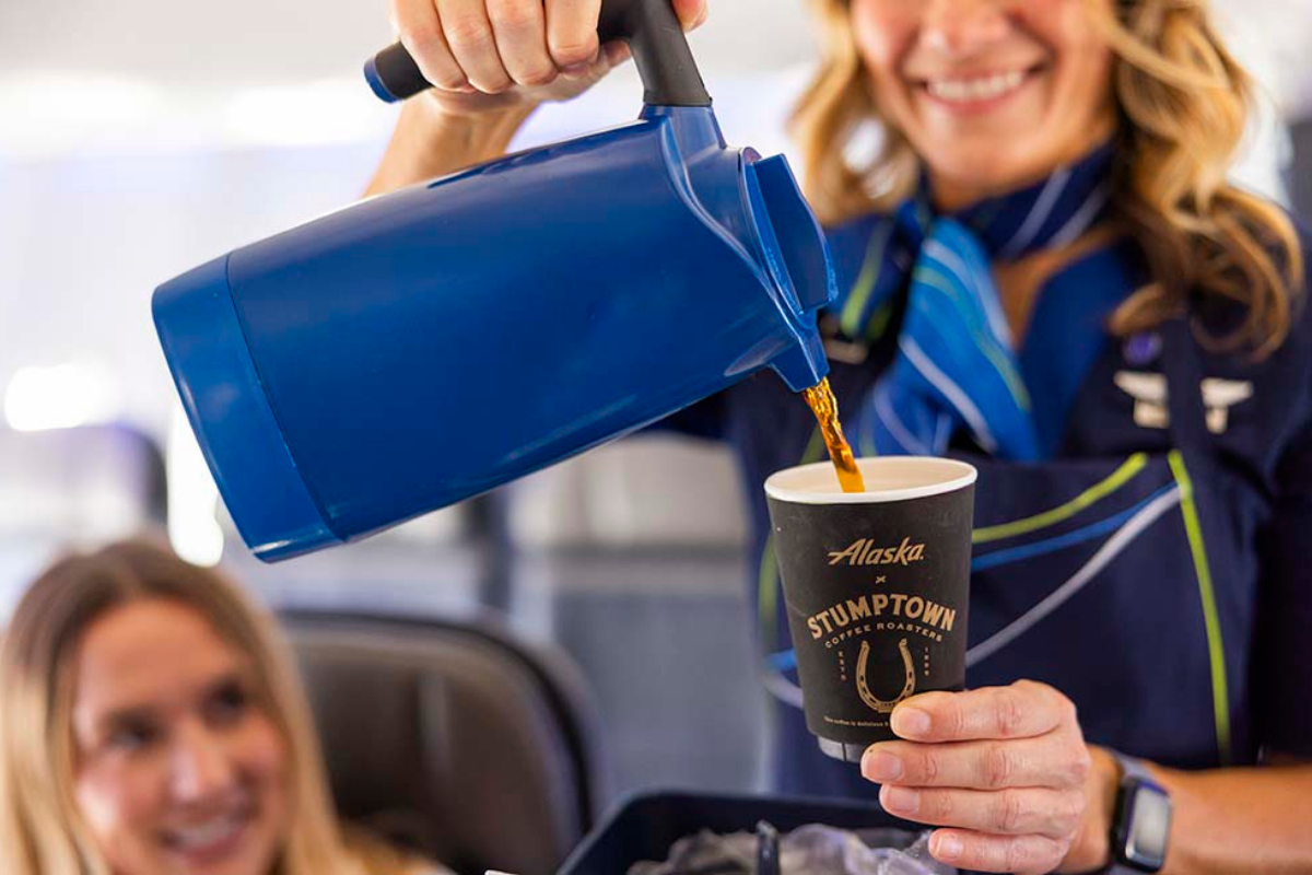 An Alaska Airlines flight attendant poring coffee