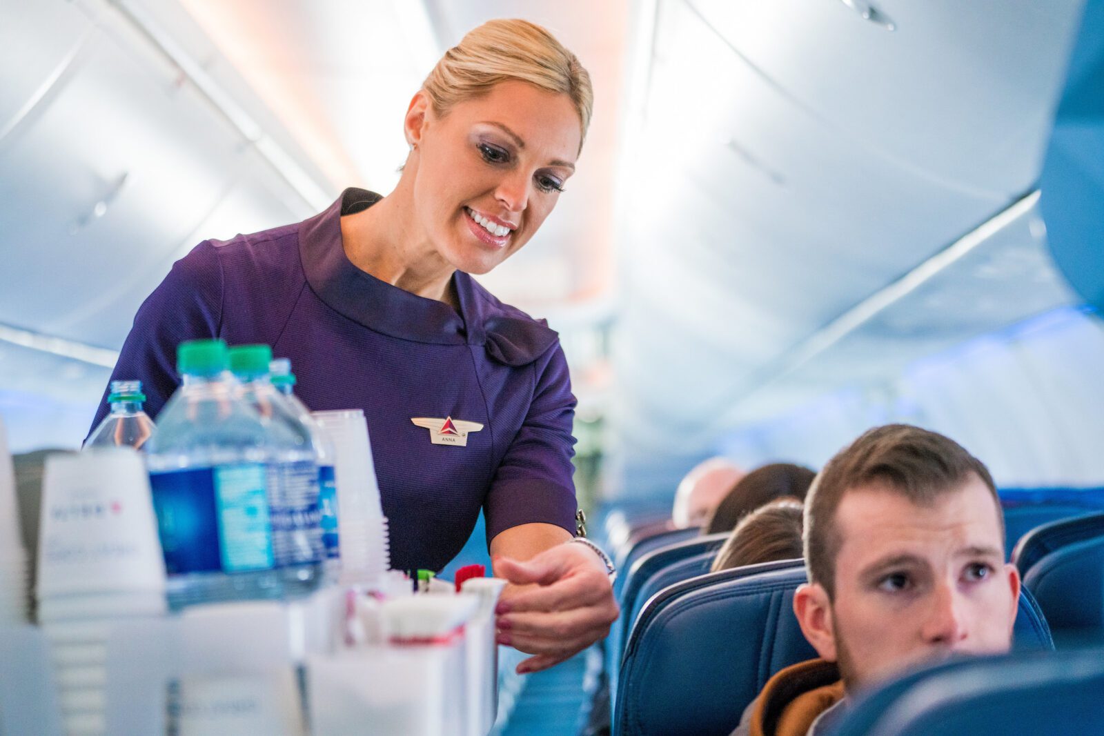 a delta air lines flight attendant performing a beverage service in the cabin