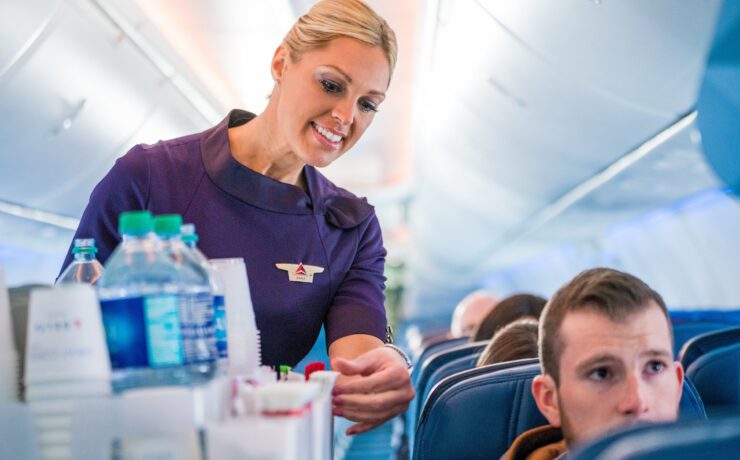 a delta air lines flight attendant performing a beverage service in the cabin