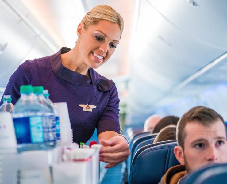 a delta air lines flight attendant performing a beverage service in the cabin